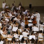 Recomanats pels professors de música, amics, coneguts o antics alumnes, tot un seguit de joves estudiants i interessats en l'àmbit de la música simfònica s'han donat cita a Cocentaina (Comtat) per gaudir de l'experiència SENT-ME durant una setmana. Procedents dels arxipèlags Canari i Balear, Catalunya, Múrcia, València o Alacant entre d'altres, els alumnes han tingut l'oportunitat de participar en activitats ben diverses i adquirir coneixements tècnics i humanístics per créixer com a músics, però també com a persones. No debades, la superació, el respecte, la reflexió i la convivència han estat els pilars fonamentals d'un festival-curs musical molt innovador.Durant la vesprada de dilluns els participants del SENT-ME varen conéixer la plantilla de professors que, durant els pròxims dies, contribuirien al seu enriquiment musical i personal. Al capdavant de l'equip, Ignacio García Vidal, organitzador del simposi, director d'orquestra, musicòleg i Doctor en Didàctica de la Direcció Musical, va estar l'encarregat de les classes de direcció musical. El contestà Jaume Llinares i l'albanés Darling Dyle assumiren la formació dels joves violins del SENT-ME; Francisco Serra, procedent del conservatori de Villena, la de les violes; Verónica Rubio i l'andalús Bruno Reyes, donaren les classes de violoncel i contrabaix respectivament. La formació dels alumnes amb instruments de vent fusta fou a càrrec de Pablo Sagredo, al capdavant de les flautes, Cayetano Castaño, amb els oboès, Eduardo Bernabeu, amb els clarinets i, finalment, Airam Déniz amb els saxos. Pel que fa al vent metall, Jesús Sánchez, Josep Olcina i Jaume Gavilán abordaren l'aprenentatge de les trompes, trompetes i trombons. Cal destacar, a més, l'especialitat d'ensenyament en música de cambra, a càrrec de la violinista internacional Anna Korpalska. Com no podia ser d'altra forma, aquest simposi també contemplà un espai per als alumnes més menuts, amb edats compreses entre els 4 i 8 anys. El "SENT-MET" va estar coordinat per Elena Huidobro, professora de piano i titulada superior en Pedagogia Musical, qui assegurà que la música esdevé fonamental per al desenvolupament personal i l'aprenentatge en la infància.Així les coses, l'Orquestra de Professors feu gala del seu talent al concert inaugural del SENT-ME, que va tindre lloc a l'escenari del Palau Comtal de Cocentaina la nit de dilluns. Tots junts, i amb la col·laboració de Rob Rowley amb les narracions, interpretaren una selecció del cèlebre "Sueño de una noche de verano" de Mendelssohn, una composició inspirada als textos literaris de William Shakespeare. 'SENT-ME', una setmana de música i germanor a Cocentaina